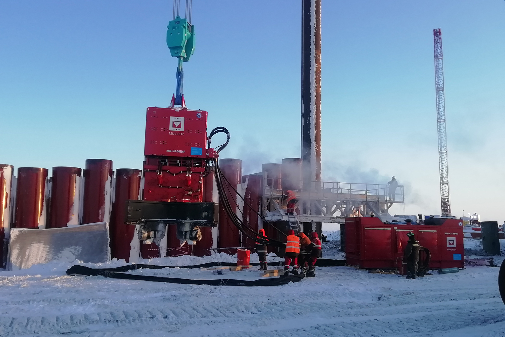 Leistungsstarke Technik auf einen Blick: Rechts im Bild ist das mit einem Winterpaket ausgestatteten MÜLLER-Aggregat MS-1150 V zu sehen. Über den Hydraulikschlauch wird die Vibrationseinheit MÜLLER MS-240 HHF angetrieben. Mit diesem Equipment lassen sich die Stahlrohre vergleichsweise einfach bis 60 Meter tief in den Permafrostboden einbringen.